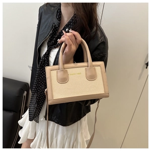 Détail du sac à main en toile beige et cuir avec anses rondes et bandoulière fine