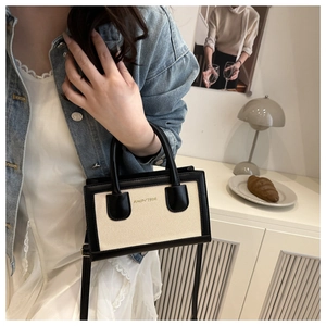 Détail du sac bandoulière rétro avec toile contrastée et cuir sur une table