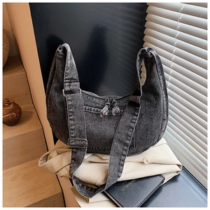 Close-up of black washed denim hobo bag with silver zipper and decorative double tassels