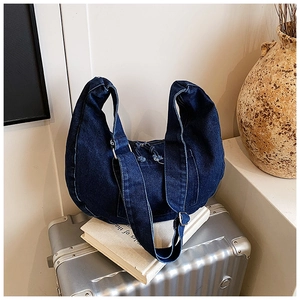 Deep blue denim hobo bag featuring wide shoulder strap and fringe zipper on metallic luggage