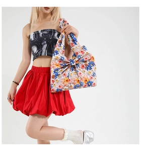 Detail of floral tote bag with colorful daisy prints and large decorative bow accessory