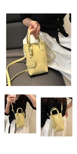 Dettaglio mini borsa gialla a mano con ciondolo a forma di cane e scritte moda donna