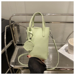 Details einer minzgrünen Mini-Tasche mit Hundeanhänger und modischem Text auf Regal
