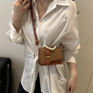 Mini brown crossbody bag with pearl handle and chain strap shown on model lifestyle
