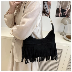Close-up of black matte suede hobo bag featuring long bohemian tassels and gold hardware