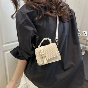 Chic mini crossbody bag with pearl handle and woven straw flap in cream finish