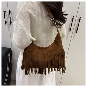 Detail of vintage brown suede shoulder bag with long fringes and gold metal buckle