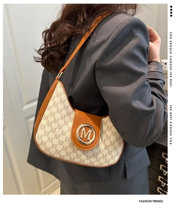 Détail du sac baguette vintage en toile avec imprimés de lettres et boucle dorée logo M porté