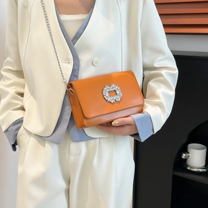 Elegant bright orange crossbody bag with rhinestone buckle and silver chain on model