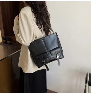 Macro detail of black vintage tote bag featuring symmetrical flap pockets and metal buckles