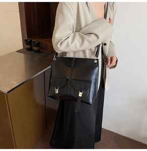 Detail shot of a black matte vintage motorcycle shoulder bag on a female model