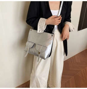 Silver metallic crossbody bag with functional buckle pockets shown on a model