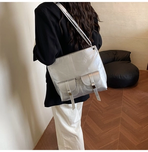 Detail of silver metallic tote bag with double front flap pockets on a shoulder strap