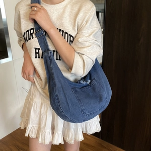 Blue denim crescent hobo bag with adjustable strap and front pocket shown on model