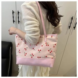 Detail of pink cherry pattern tote bag with leather base and long shoulder strap