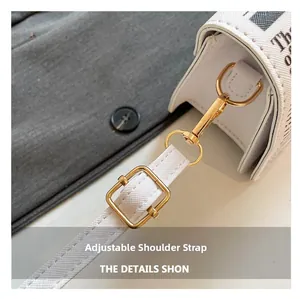 Detail of newspaper print crossbody bag featuring adjustable golden metal hardware