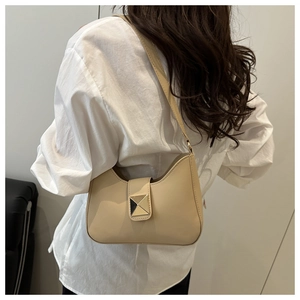 Detail view of stylish beige hobo bag with gold square buckle worn as a shoulder bag