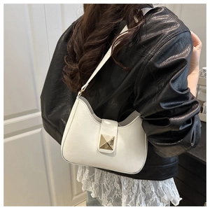 Detailed view of white crescent bag featuring a prominent gold pyramid metal buckle