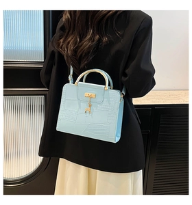Close-up of light blue crocodile embossed square bag with gold deer pendant detail