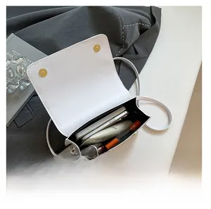 Internal view of a small white crossbody bag showing storage for phone and cosmetics