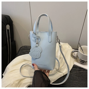 Detail of light blue mini vertical bucket bag with cute puppy charm on silk fabric