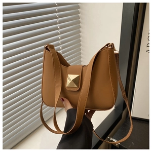 Detail of caramel brown hobo bag featuring a gold square pyramid clasp and leather strap
