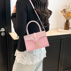 Pink leather handbag with glittery rhinestones and gold lock shown in a lifestyle setting
