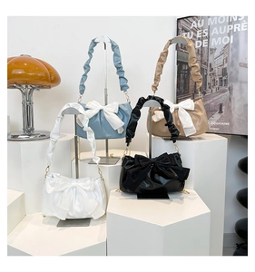 Detail of stylish bow shoulder bags in white, blue, black, and khaki with scrunchie handles