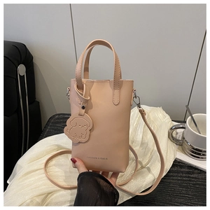Detailed view of pink mini bucket bag with soft leather texture and dog charm