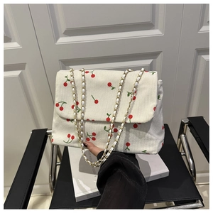 Détail du sac cabas en velours côtelé blanc avec motifs cerises et bandoulière chaîne