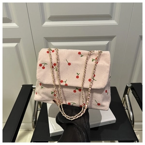 Vue détaillée du velours côtelé rose avec broderie cerise et bandoulière chaîne dorée