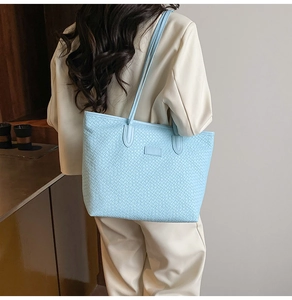 Detailed view of light blue woven tote bag on shoulder showing the intrecciato pattern texture