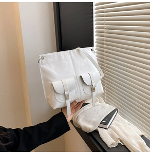 Détail du sac à épaule en cuir blanc avec poches utilitaires et lanières décoratives