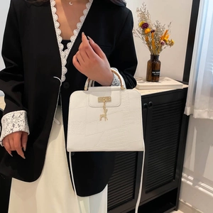 Elegant white crocodile texture handbag with gold handles shown on a stylish woman