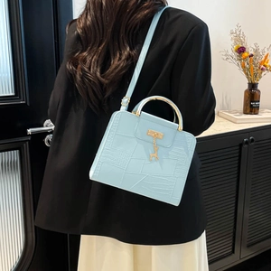 Light blue textured crossbody bag with gold deer charm and metallic top handle