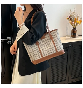 Klassische Canvas-Einkaufstasche mit braunem Lederbesatz, getragen von einem Modell im Blazer