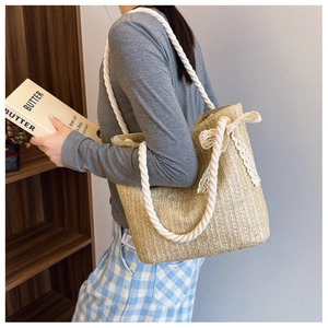 Detail of hand-woven straw tote bag with lace bow and sturdy cotton rope handle