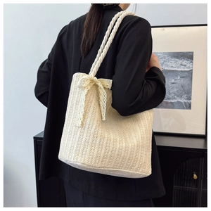 Close-up of cream straw woven tote bag featuring delicate lace bow and thick rope handles