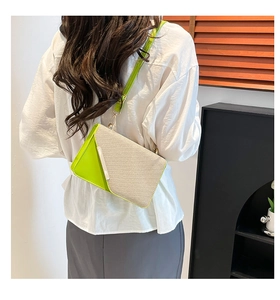 Détail d'un sac bandoulière en cuir vert et tissu tissé beige porté par un mannequin