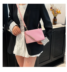 Détail du sac bandoulière enveloppe en cuir rose clair avec garniture métallique et boucle d'or