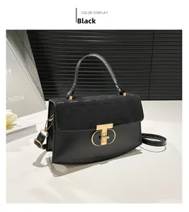 Detail of black crossbody bag featuring monogram texture and golden T-shaped metal lock