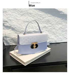 Detail of light blue crossbody bag with T-shaped gold clasp and embossed texture