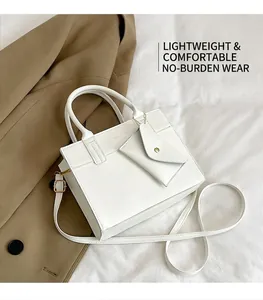 Detail of white leather tote featuring dual round handles and envelope charm attachment