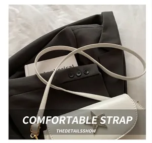 Detail showing the white leather crossbody bag featuring a metallic star and thin strap