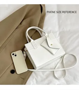 Close-up of white PU leather square handbag with mini pouch and gold buckle detail