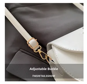 Detail of white leather shoulder bag featuring adjustable gold buckle and fine stitching