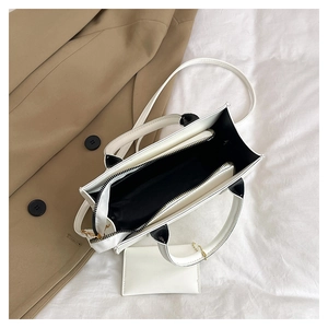 Detailed top view of a white leather tote with black interior and small zipper pouch