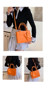 Detail of orange crossbody tote bag with envelope pendant and embossed fashion text