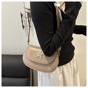 Side view of beige crossbody bag with rhinestone star on leather strap on a model