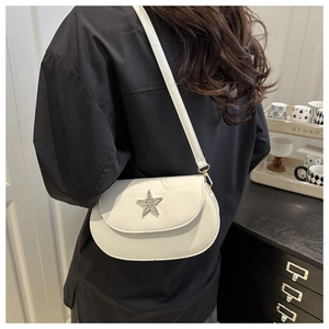 Close-up of white leather saddle bag with silver rhinestone star decoration worn on shoulder